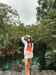Tanned woman in a breezy vacation outfit with a hat, enjoying a tropical getaway