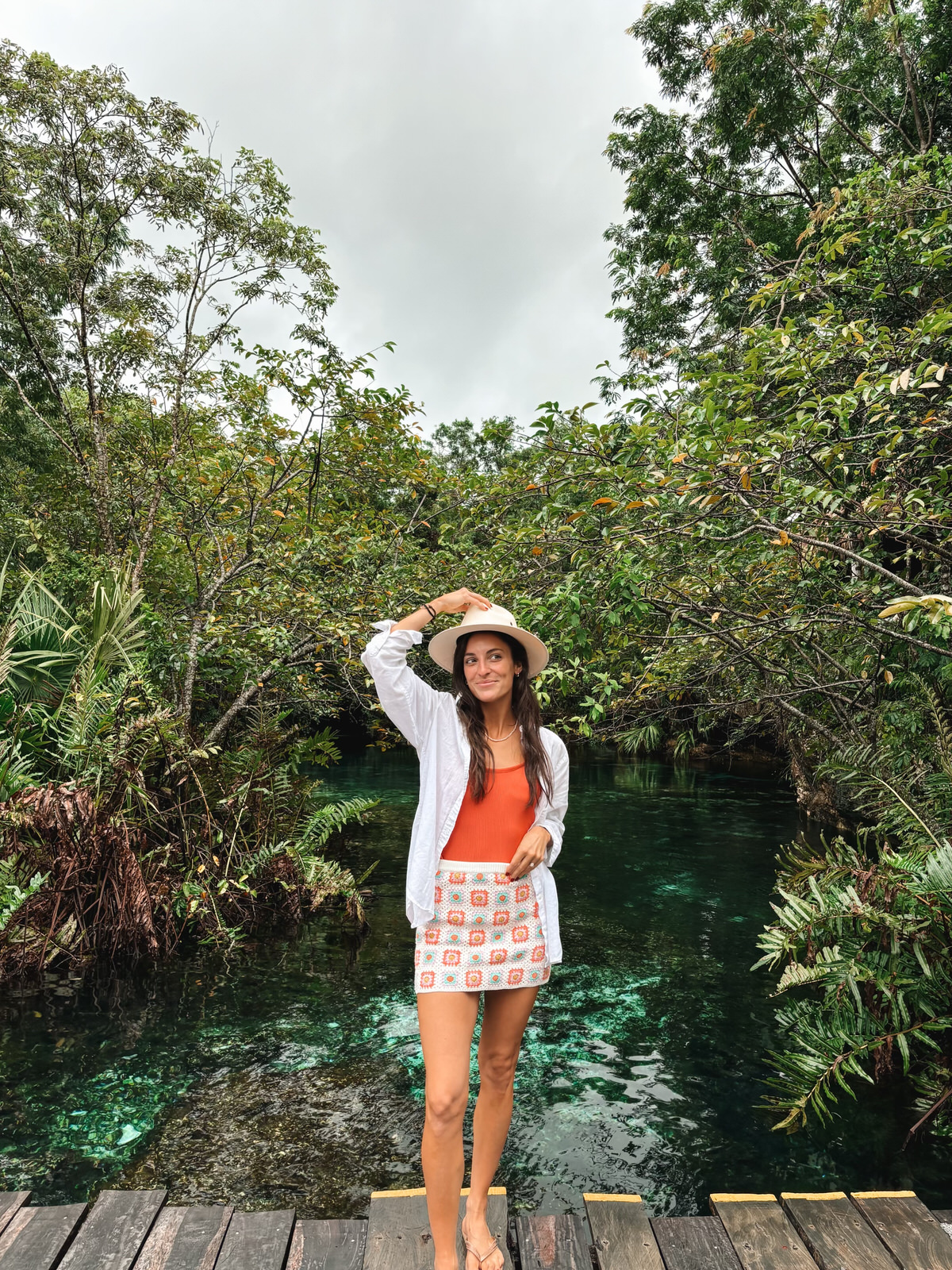 Tanned woman in a breezy vacation outfit with a hat, enjoying a tropical getaway