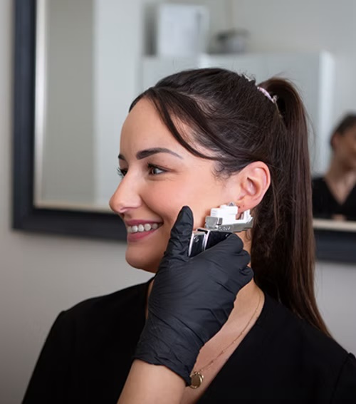 Smiling woman receiving safe and gentle ear piercing with Studex System 75 in a calm, professional environment