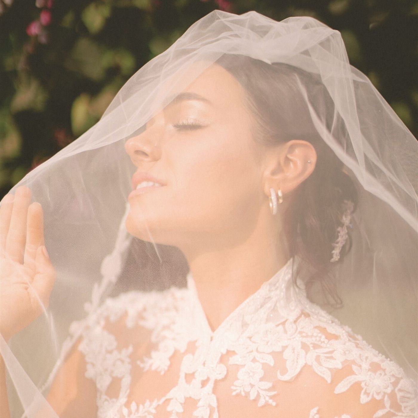 Bride with glowing sun-kissed skin under a delicate lace veil, captured in warm natural light after a sunny daze sunless spray tan in Lawrence, Kansas.